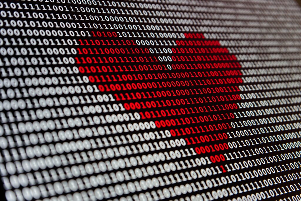 Binary code in black and white fills the screen, forming a red heart shape in the center. The heart is composed of zeros and ones, symbolizing digital technology and love or emotion in programming.
