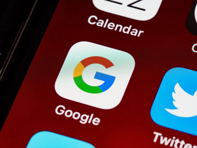 Close-up of a smartphone screen displaying apps, focusing on the Google app icon in the center. The icons for Calendar and Twitter are also partially visible on a red background.